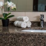 Stylish bathroom with granite sink, rolled towels, and a potted orchid.